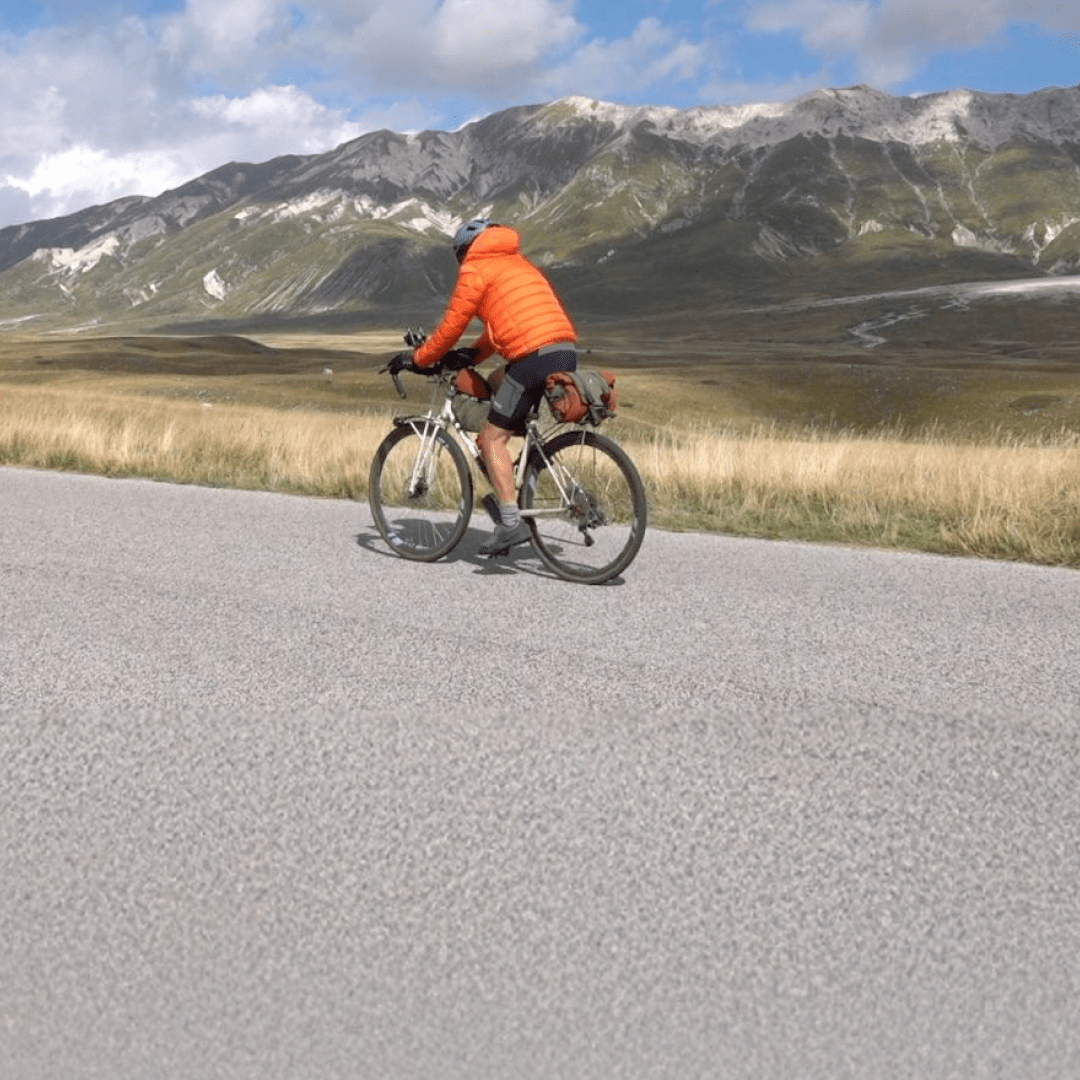 homme qui fait du vélo sur une route avec une montagne en fond